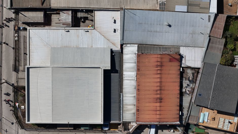 Aerial view of various industrial warehouse roofs with different textures and colors.
